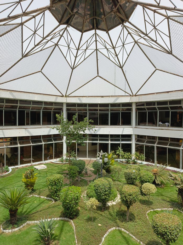 Lush green courtyard inside a building with a unique geometric roof design.
